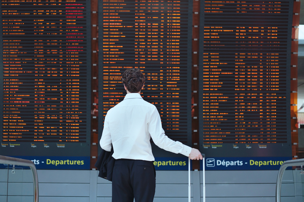 Passenger standing in front of a large flight board.