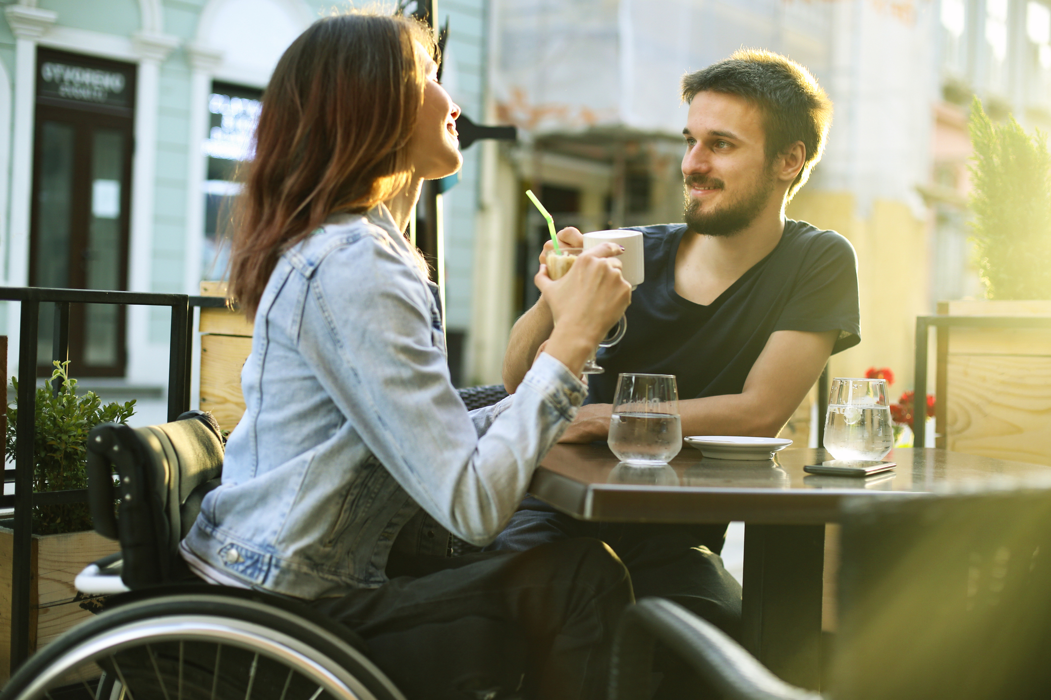 Woman using wheelchair sips coffee with her boyfriend.
